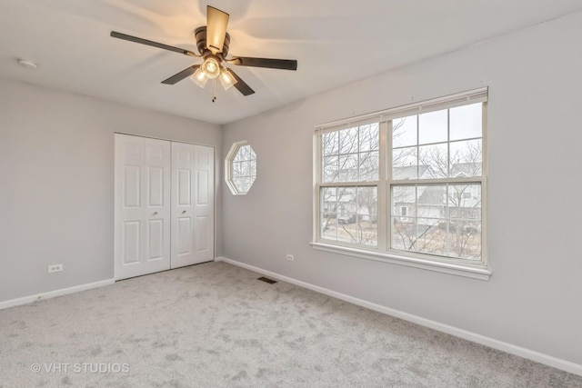 unfurnished bedroom featuring a closet, visible vents, carpet flooring, ceiling fan, and baseboards