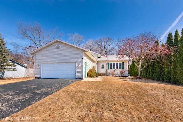 ranch-style house featuring a garage, aphalt driveway, and a front yard