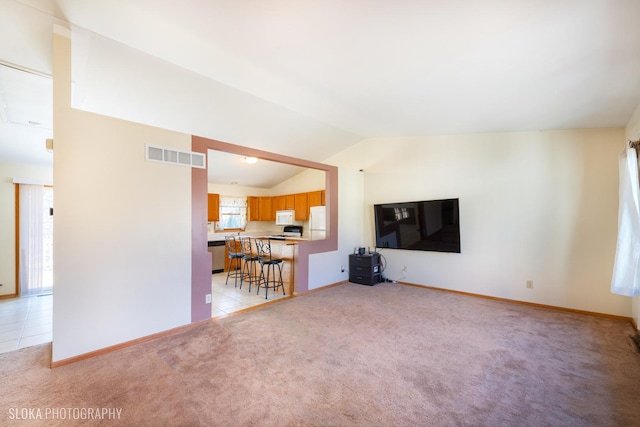 unfurnished living room with light tile patterned floors, lofted ceiling, light carpet, visible vents, and baseboards