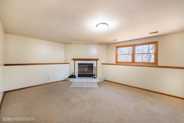 unfurnished living room with carpet floors, visible vents, a fireplace, and baseboards