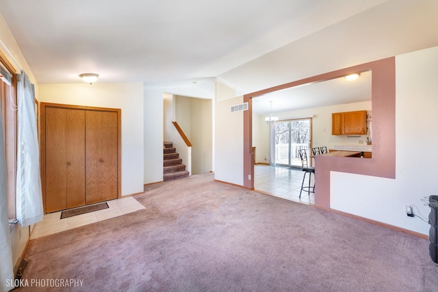 unfurnished living room featuring visible vents, light colored carpet, vaulted ceiling, and stairway