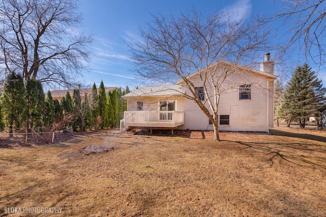 back of property with a chimney, fence, and a wooden deck