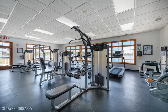 exercise room with a paneled ceiling, visible vents, and baseboards