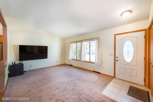 carpeted entrance foyer featuring tile patterned flooring, visible vents, vaulted ceiling, and baseboards