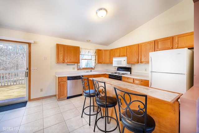 kitchen featuring light tile patterned floors, light countertops, white appliances, and a sink