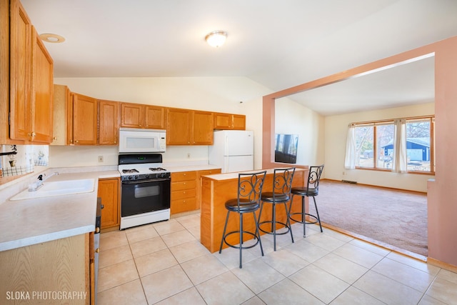 kitchen featuring a breakfast bar area, light carpet, white appliances, a sink, and light countertops