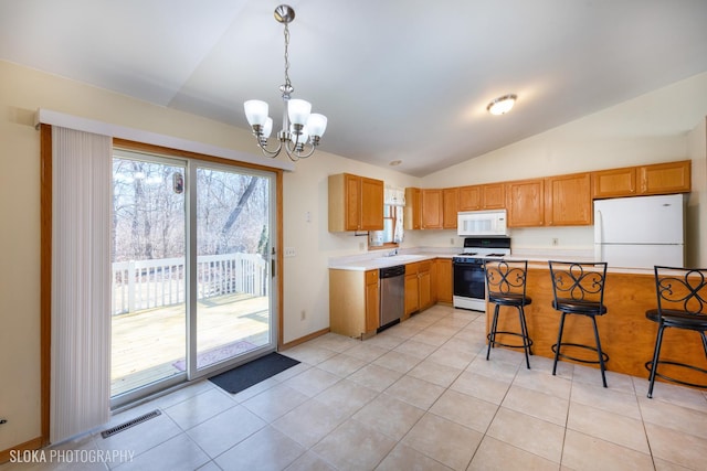 kitchen with a breakfast bar area, white appliances, a sink, light countertops, and pendant lighting