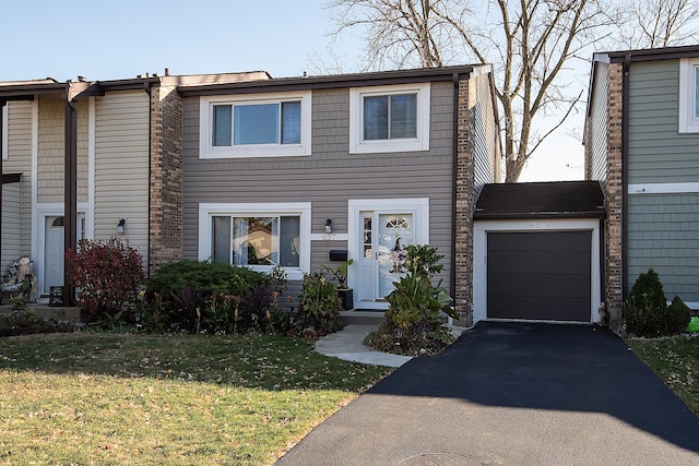 view of property with driveway, an attached garage, and a front yard