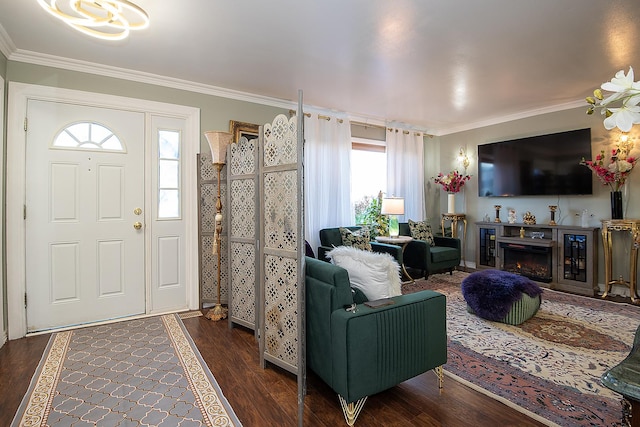 entrance foyer with crown molding, wood finished floors, and a lit fireplace