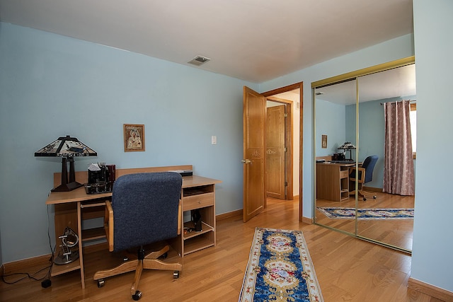 office space featuring light wood-type flooring, visible vents, and baseboards