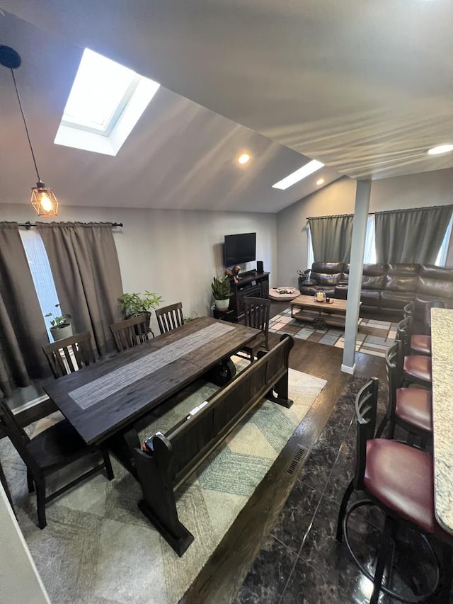 dining area with vaulted ceiling with skylight, recessed lighting, and wood finished floors