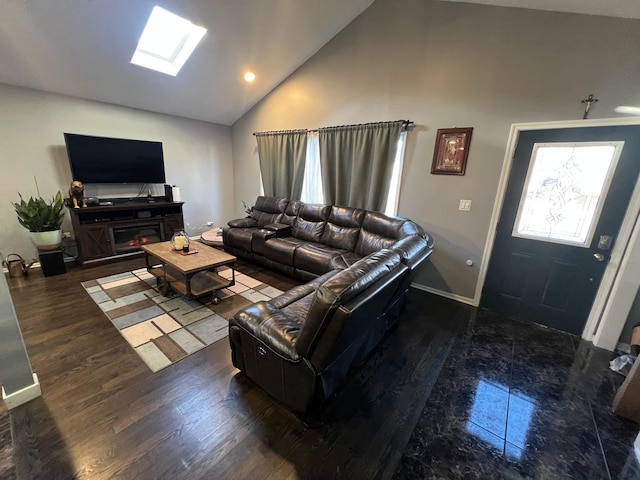 living area with lofted ceiling with skylight, baseboards, wood finished floors, and a glass covered fireplace