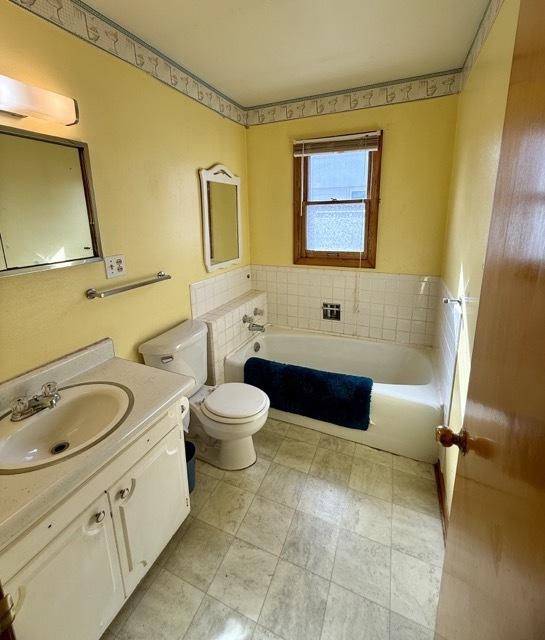 full bathroom with vanity, toilet, and a bath