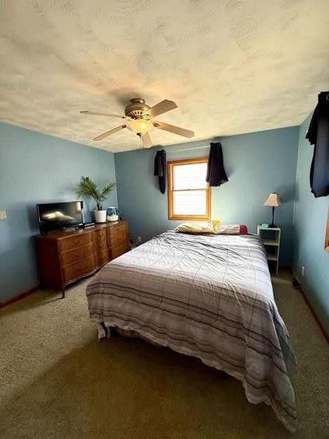 carpeted bedroom with ceiling fan, baseboards, and a textured ceiling