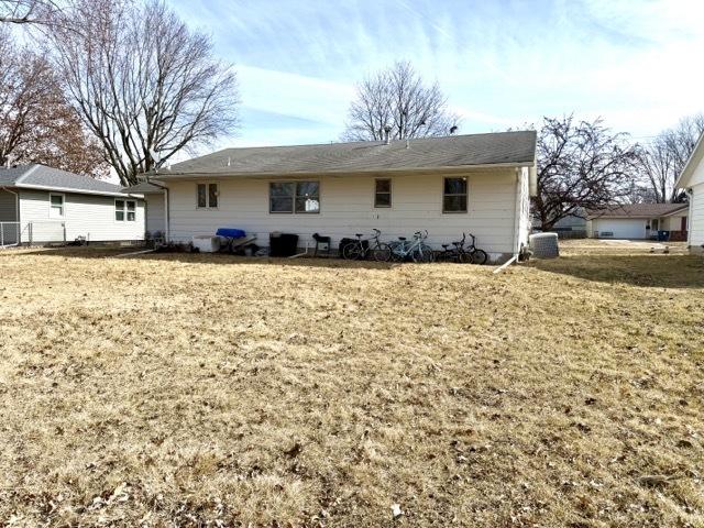 back of property with central air condition unit and a yard