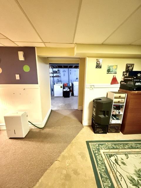 hall with a paneled ceiling and washer / dryer