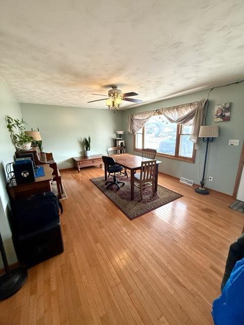 dining space with wood-type flooring, visible vents, ceiling fan, and a textured ceiling