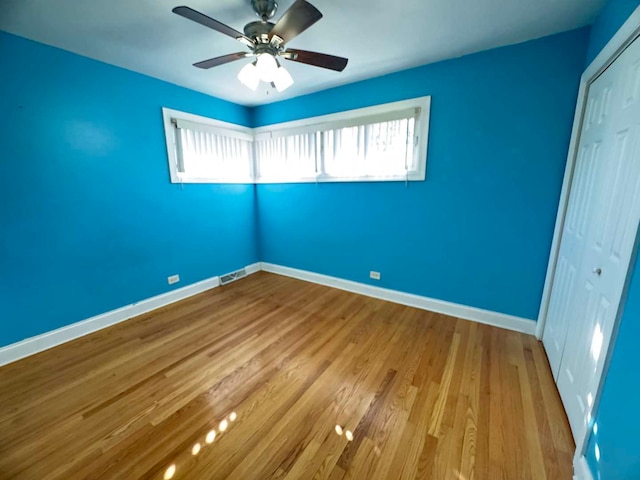 unfurnished bedroom with baseboards, visible vents, a ceiling fan, wood finished floors, and a closet