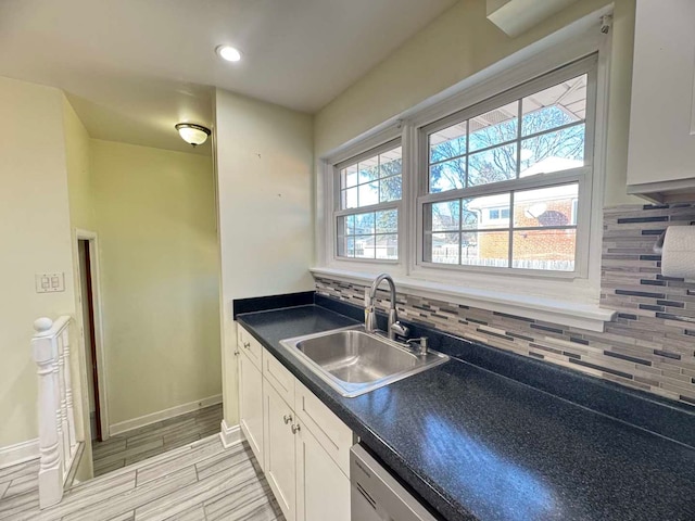 kitchen featuring dark countertops, a sink, white cabinetry, and decorative backsplash