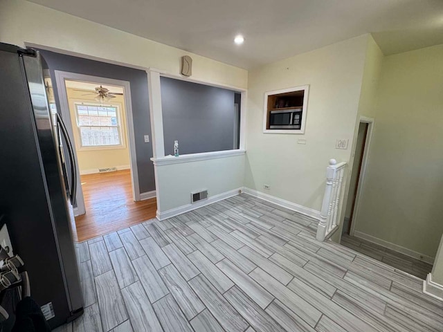 interior space with wood finish floors, visible vents, ceiling fan, and baseboards