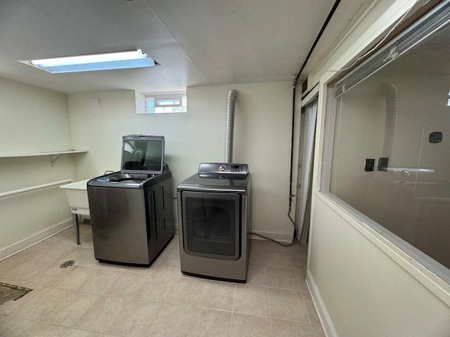 washroom with washing machine and dryer, laundry area, light tile patterned flooring, and baseboards