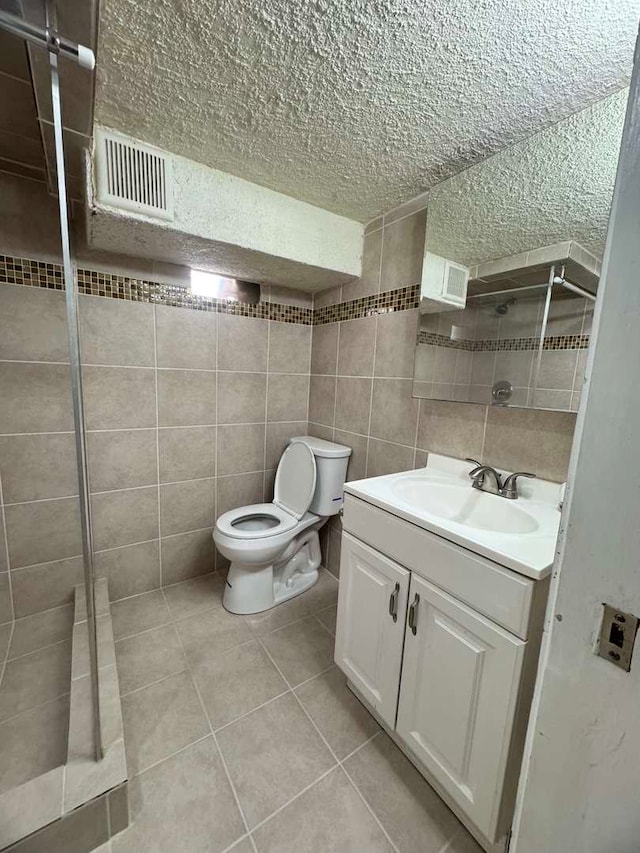 full bathroom featuring visible vents, toilet, tile patterned floors, vanity, and tile walls