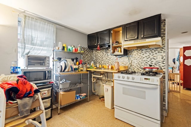 kitchen with light floors, stainless steel microwave, decorative backsplash, white range with gas cooktop, and under cabinet range hood