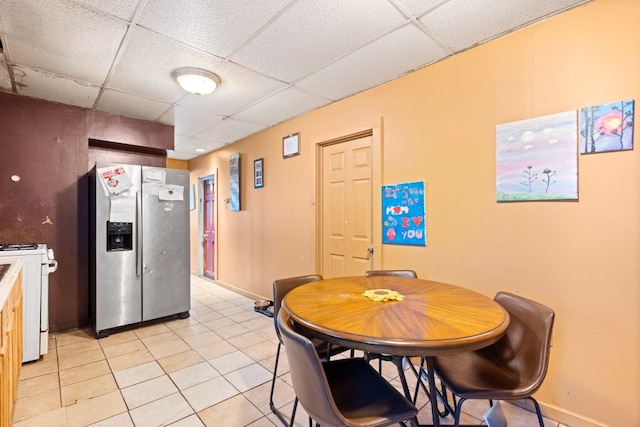 dining room featuring light tile patterned floors, a paneled ceiling, and baseboards