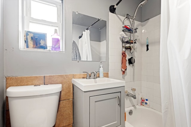 bathroom with shower / bath combo, tile walls, vanity, and toilet