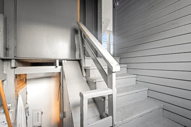 stairway featuring wood walls