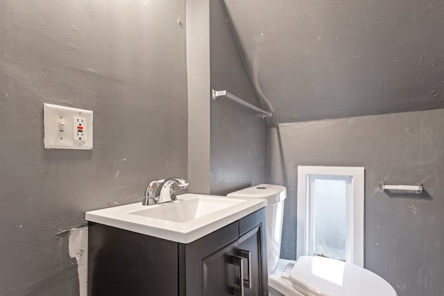 bathroom with a textured wall, vanity, and toilet