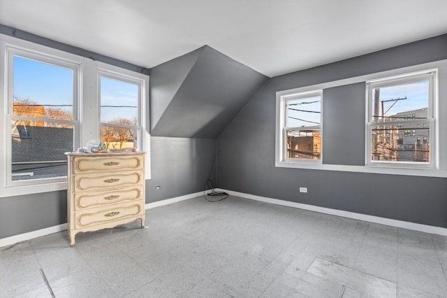 additional living space featuring vaulted ceiling, light floors, and baseboards