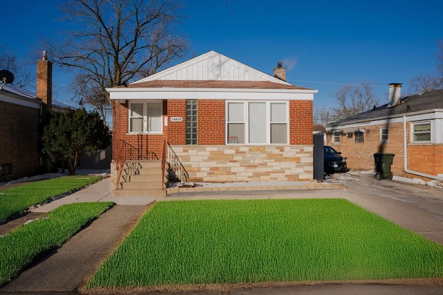 bungalow-style house with a front yard, a chimney, and brick siding