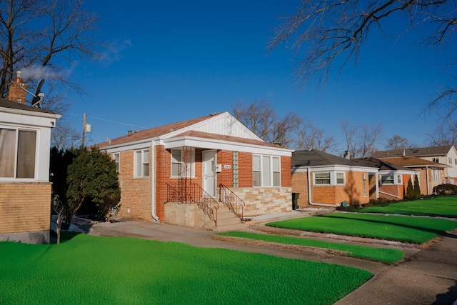 bungalow featuring brick siding and a front yard