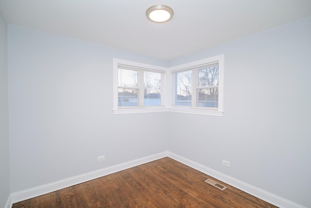 empty room featuring visible vents, dark wood finished floors, and baseboards