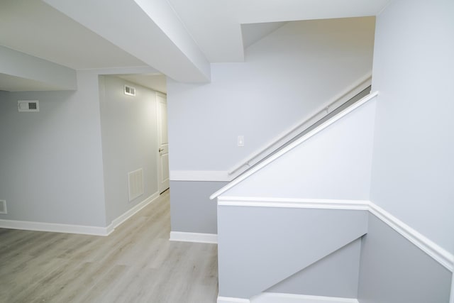 corridor featuring light wood-style flooring, visible vents, and baseboards