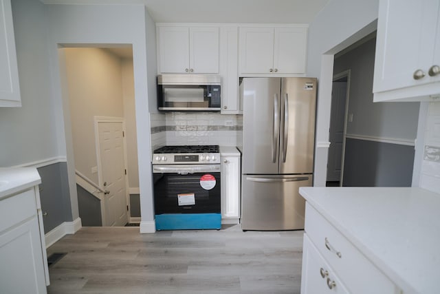 kitchen with white cabinetry, appliances with stainless steel finishes, light countertops, and decorative backsplash