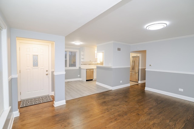 interior space with visible vents, baseboards, wood finished floors, and ornamental molding