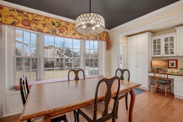 dining area featuring light wood-type flooring, built in desk, a chandelier, and crown molding