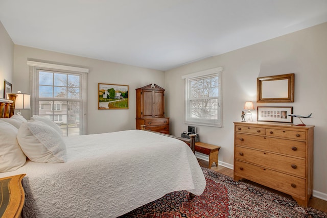 bedroom with multiple windows, baseboards, and wood finished floors