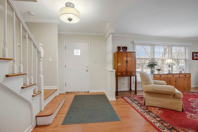 entryway featuring ornamental molding, light wood-style flooring, baseboards, and stairs