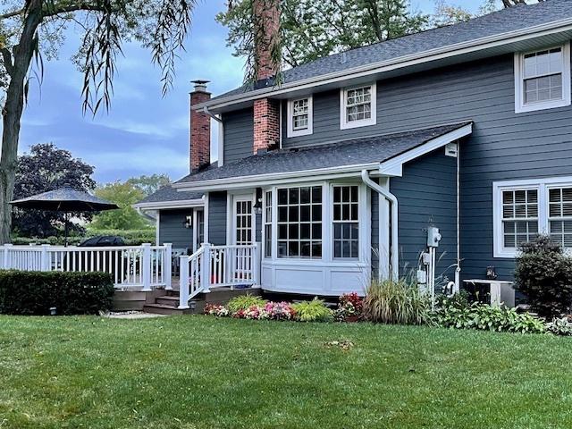 view of front of property with a front yard, a chimney, and a wooden deck