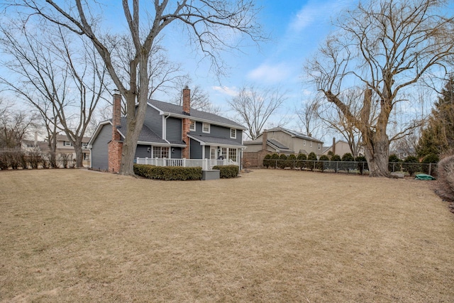 back of property featuring a chimney, fence, and a yard
