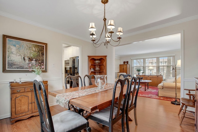dining room with crown molding, a chandelier, and light wood-style floors