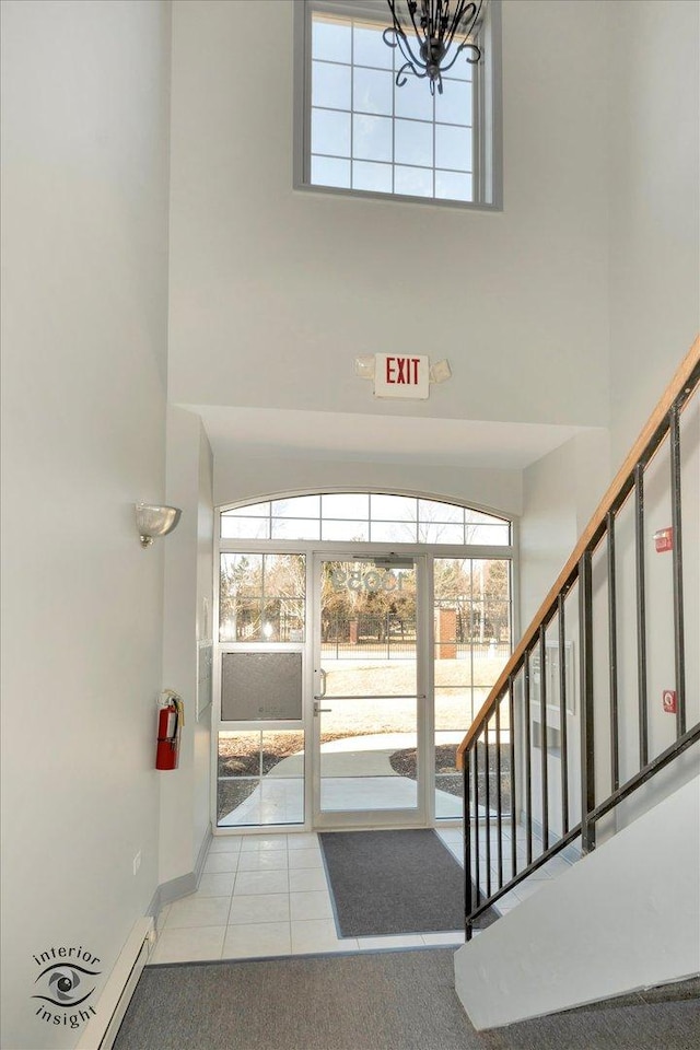 stairway featuring a chandelier, tile patterned flooring, a towering ceiling, and baseboards