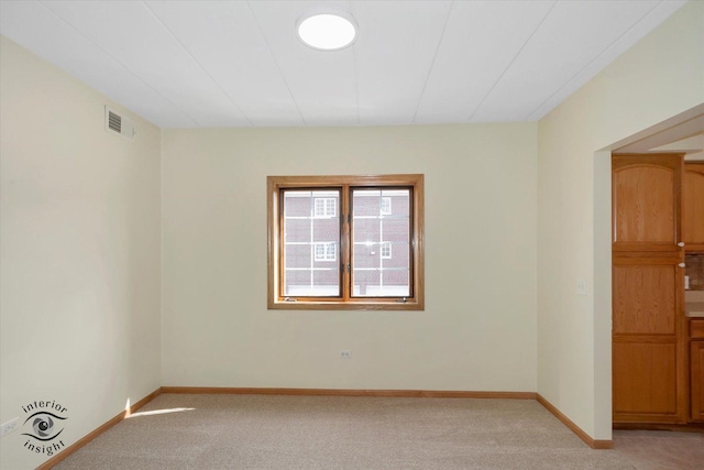 unfurnished room with light carpet, visible vents, and baseboards