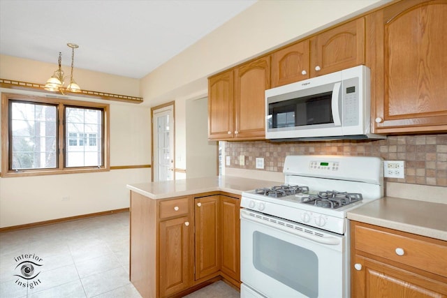 kitchen featuring white appliances, baseboards, a peninsula, light countertops, and backsplash