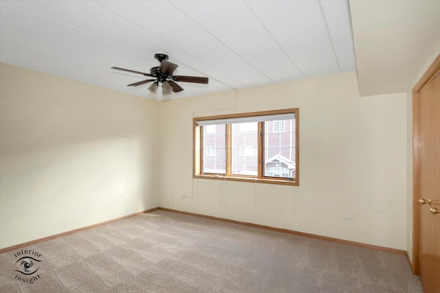 spare room featuring light carpet, ceiling fan, and baseboards