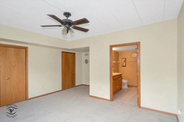 unfurnished bedroom with visible vents, baseboards, ensuite bathroom, and light colored carpet