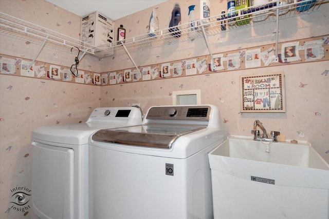 washroom with laundry area, washer and dryer, and a sink